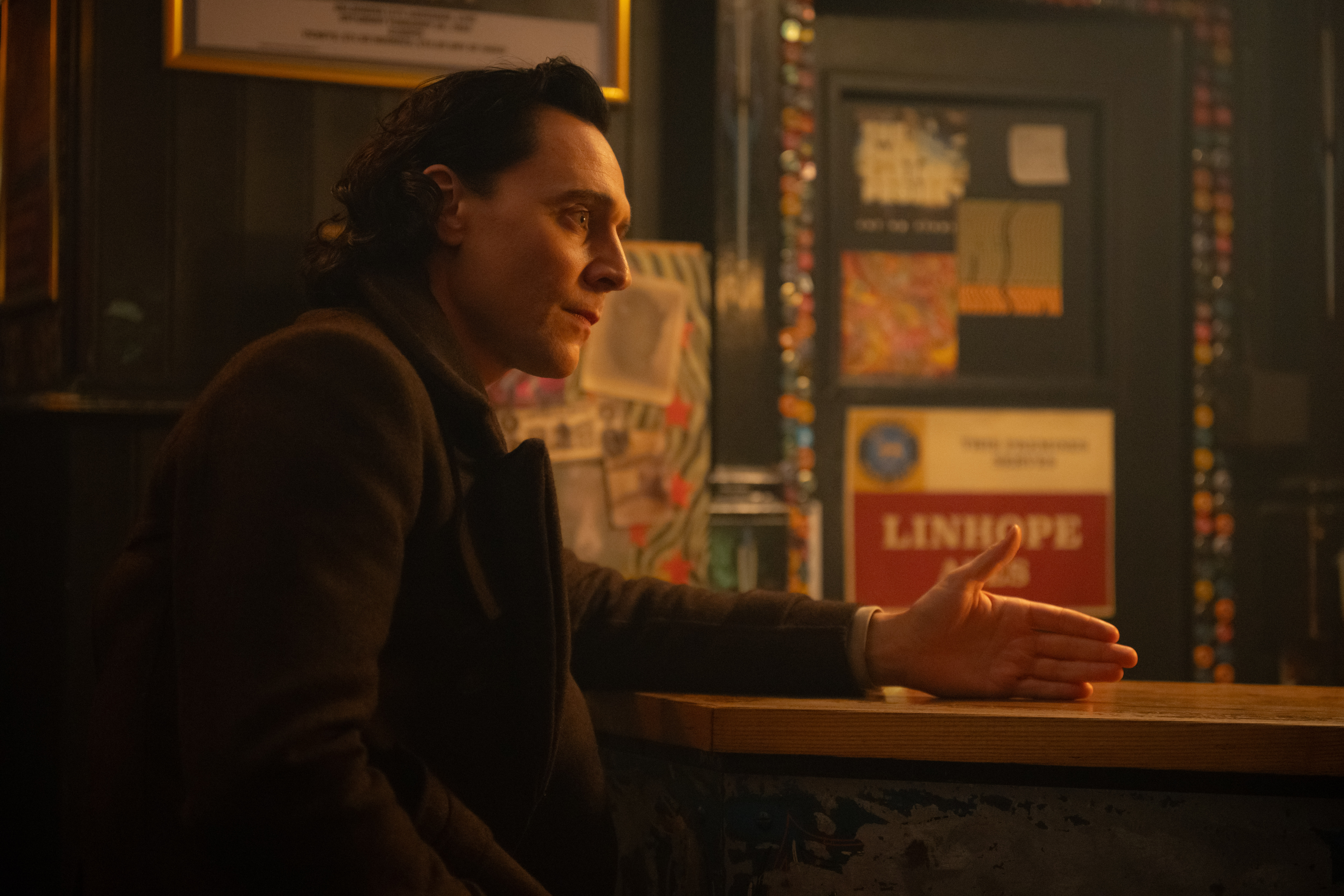 Loki (Tom Hiddleston) sitting at a counter