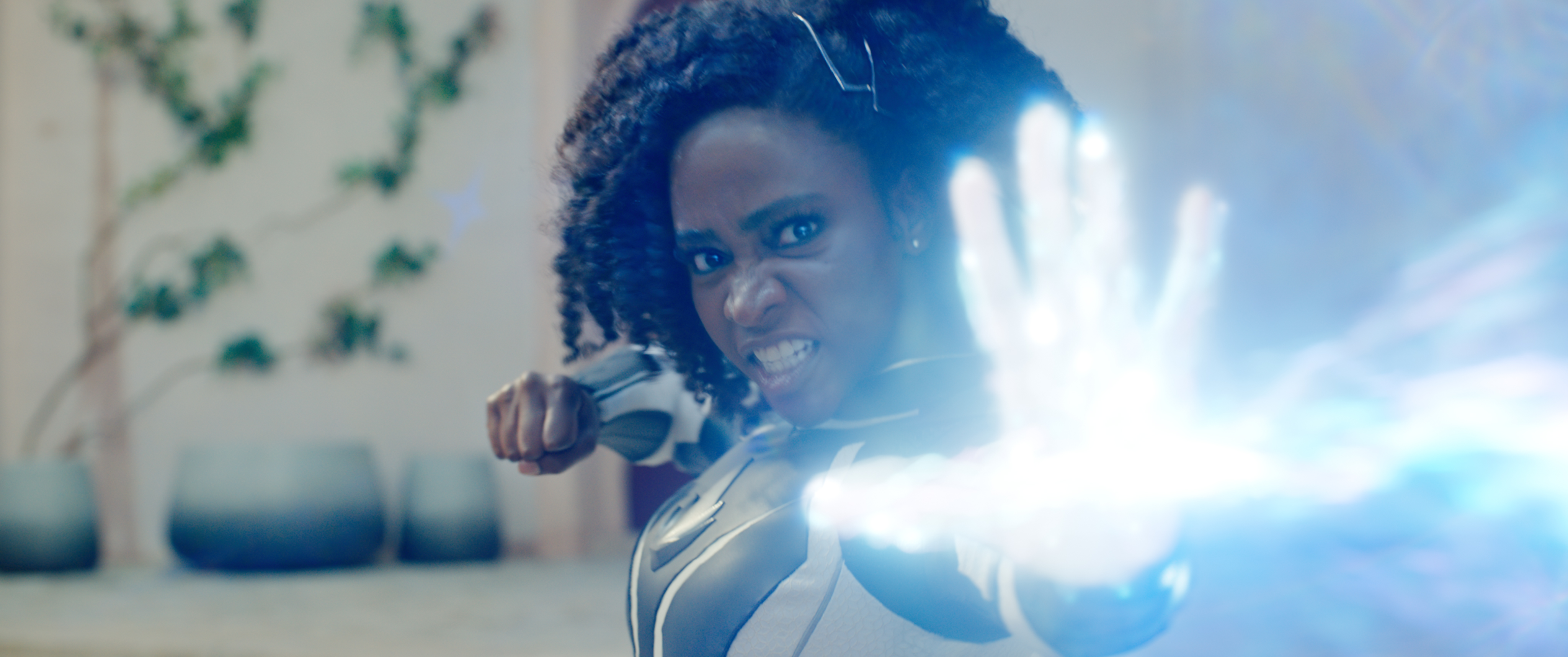 Teyonah Parris as Captain Monica Rambeau snarls as she blasts an offscreen foe with a white blast of glowing light in the Marvel Cinematic Universe movie The Marvels