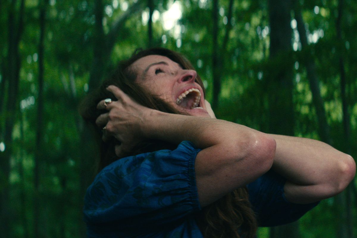 Julia Roberts covers her ears and screams in pain in the woods in the Netflix film Leave the World Behind
