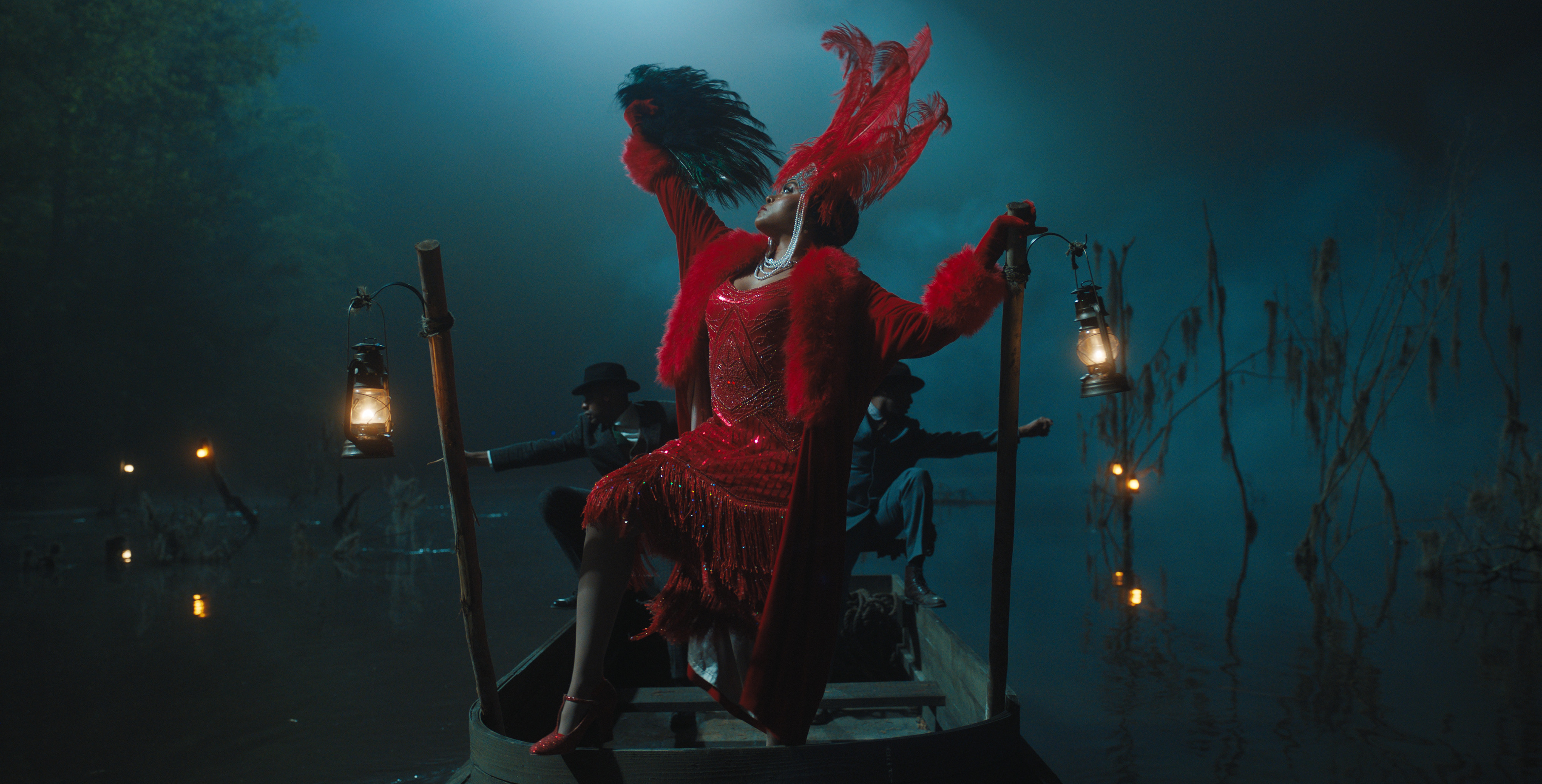 Shug Avery (Taraji P. Henson) arrives at a juke joint in style, riding a skiff in a red sequined dress and feathered hat and posing dramatically with a feathered fan in the musical version of The Color Purple