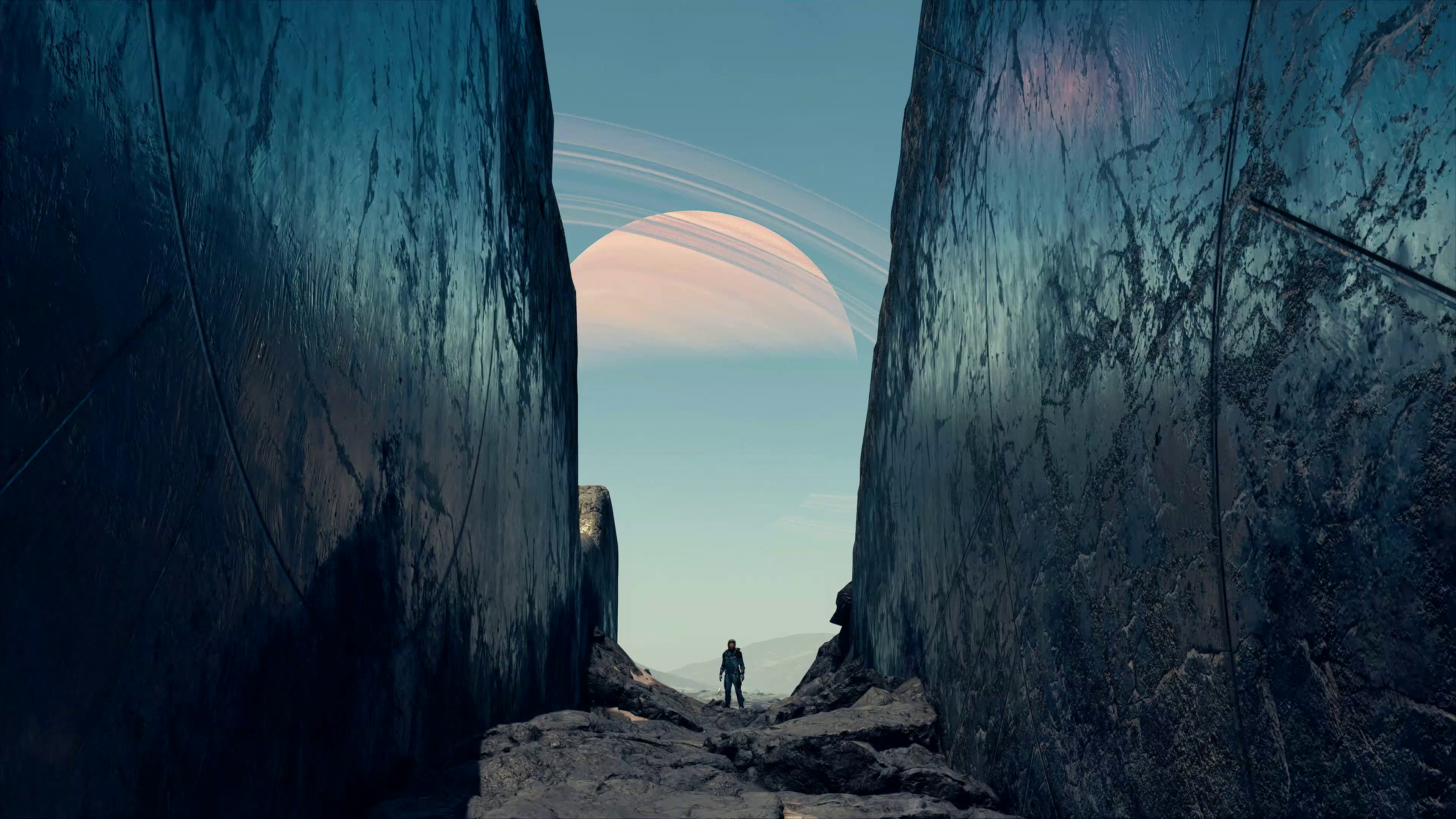 A screenshot of Starfield, showing a space explorer standing in a valley with a ringed planet visible in the atmosphere